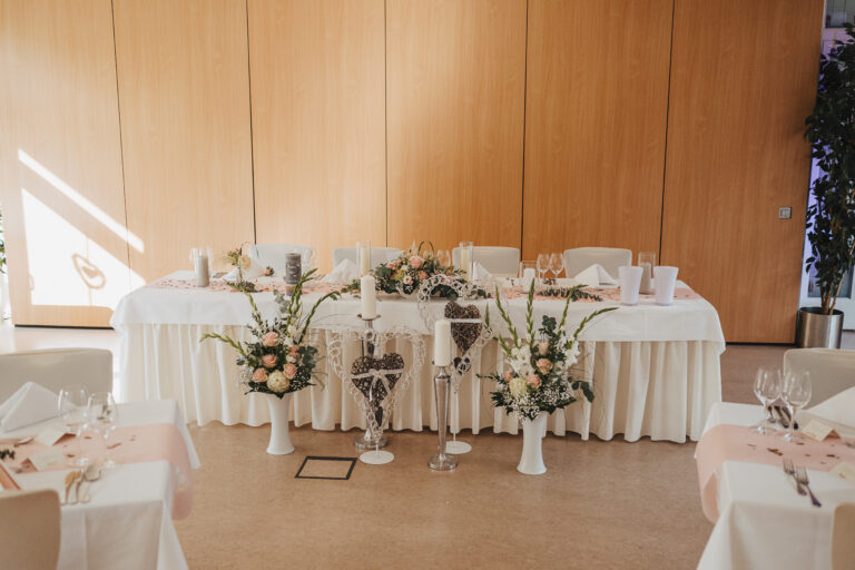 Brauttisch im Hotel Silberbach mit Holzoptik Hintergrund und Blumenarrangements