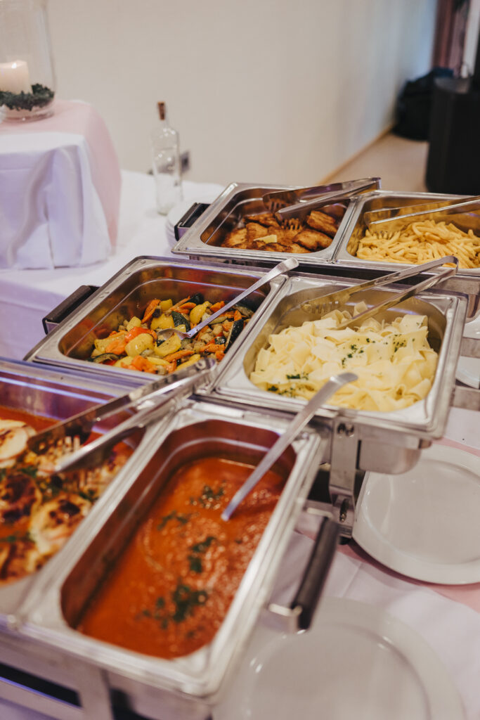 Buntes Buffet mit Edelstahltanks, Gemüsepfanne, Nudeln und Tomatensauce auf einem festlich gedeckten Tisch; Haus Silberbach bzw. Hotel Silberbach als Kontextname