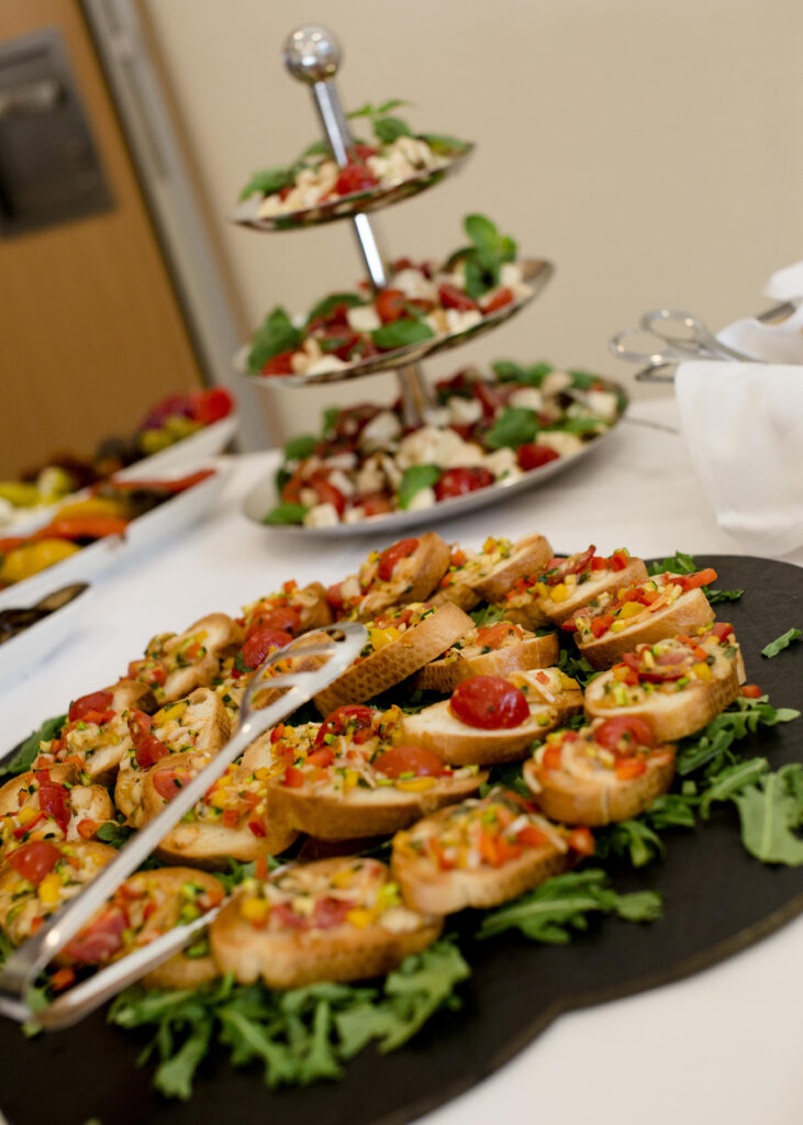 Bunte Buffetplatte mit Bruschetta und Antipasti auf dunkler Servierplatte, hintere Ebenen mit Salatarrangements – Hotel Silberbach