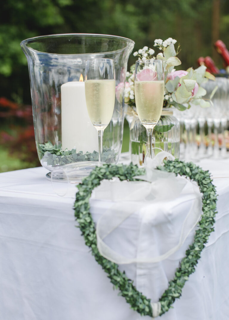 Sektempfang bei Hochzeiten im Hotel Silberbach: Gläser, Kerzen und Herzkranz auf weißem Tisch