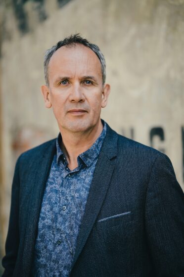 Porträt des Schriftstellers Volker Kutscher bei der Kulturreihe im Hotel Morgenland vor einer historischen Gebäudefassade